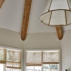 a living room filled with furniture and two windows covered in roman blind shades on top of them