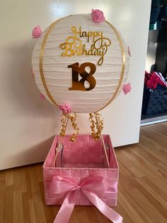 a birthday card box with pink ribbon and gold foil on the inside, sitting on a wooden floor in front of a white wall