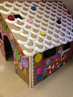 a cardboard house made to look like a gingerbread house with decorations on the roof