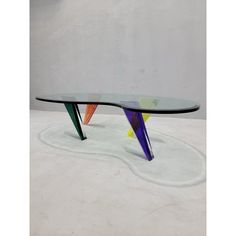 a modern glass table with multicolored shapes on the top and bottom, against a white background