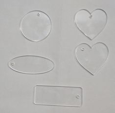 four clear heart shaped tags on a white surface with holes in the middle to cut them