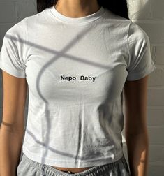 "Baby tee with embroidered Nepo Baby text Model is wearing  size S in the white tee and is a 6/8 - For reference, model is 5'5 with 31\" bust and 26\" waist 100% cotton" Cotton Cropped T-shirt With Embroidered Logo, Crew Neck Cropped Cotton T-shirt With Embroidered Logo, Cotton Cropped T-shirt With Embroidered Logo, Crew Neck, Fitted White T-shirt With Text Print, Casual Cropped Cotton T-shirt With Embroidered Logo, Casual Cropped T-shirt With Embroidered Logo, Basic Short Sleeve Top With Embroidered Logo, Fitted Crew Neck Tops With Embroidered Text, Fitted White T-shirt With Logo Print