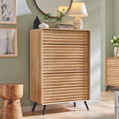 a wooden cabinet sitting in front of a mirror on top of a dresser next to a lamp