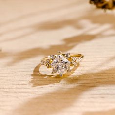 a diamond ring sitting on top of a wooden table next to a pine tree branch