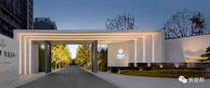 an entrance to a building with white walls and lights on the sides, in front of trees