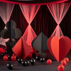 red and black balloons are in the shape of heart shapes on a stage with sheer drapes