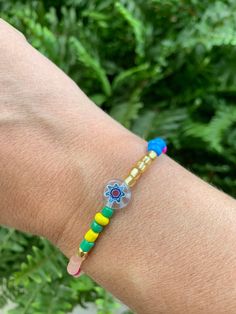 "Millefiori means \"a thousand flowers\" in Italian. The clear flower bead is surrounded by bright and colorful seed beads. Perfect for stacking!  Approx 6.5\" long" May 11, Beaded Flowers, Seed Beads, Jewelry Bracelets, Seeds, Etsy Accessories, Accessory Gift, Beaded Bracelets, Electronic Accessories