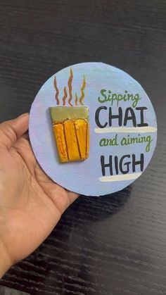 a hand holding up a sticker that says, sipping chat and aiming high