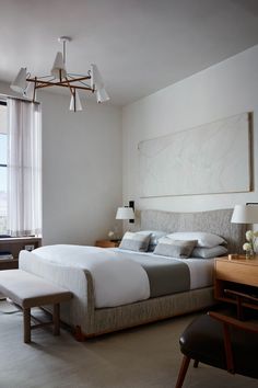 a bedroom with a large bed and two lamps hanging from the ceiling over it's headboard