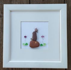 a white frame holding a rock and flowers