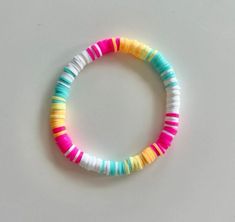 a bracelet made out of multicolored plastic beads on a white surface with one bead in the middle