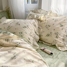 an unmade bed with green and white sheets, pillows and a pillow case on it