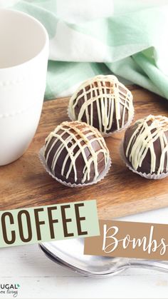 three chocolate covered donuts sitting on top of a wooden cutting board next to a cup