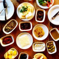 the table is full of different types of food and condiments, including olives