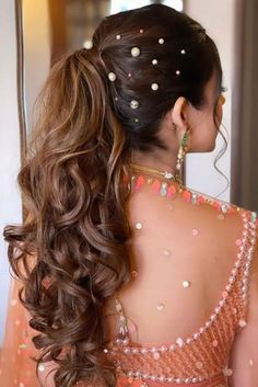 a woman with long hair in a ponytail and pearls on her head, wearing an orange dress