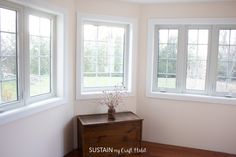 a room with three windows and a wooden table