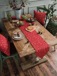 a wooden table topped with plates and bowls filled with food next to green chairs in front of a potted plant