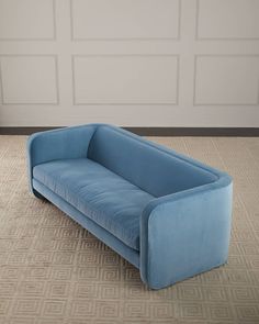 a blue couch sitting on top of a carpeted floor next to a white wall