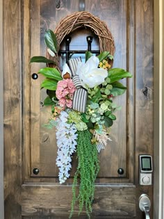 a wreath with flowers and greenery hangs on the front door to an entranceway