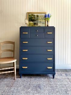 a blue dresser sitting next to a wooden chair