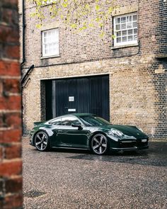 a green sports car parked in front of a brick building