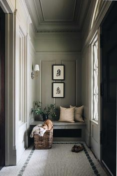 a dog laying on the floor in front of a window with two pictures above it