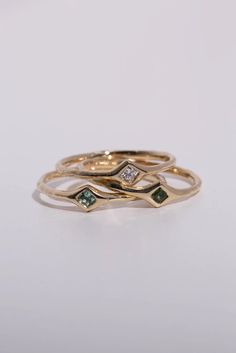 three gold rings with green and white stones on top, one is in the shape of leaves