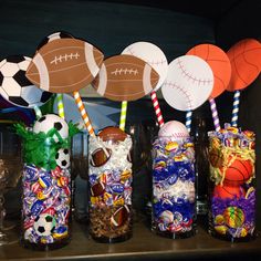 sports themed candy jars with paper straws and lollipops in them on a shelf