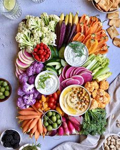 a platter filled with assorted vegetables and dips on top of a table