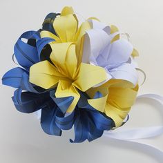 a bridal bouquet with blue, yellow and white paper flowers on the top of it