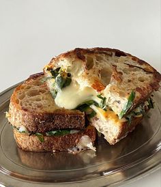 a grilled cheese and spinach sandwich on a silver plate with a white background