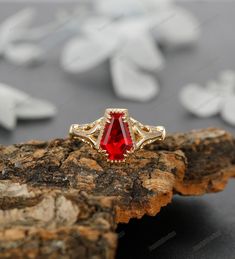 a red stone ring sitting on top of a piece of wood