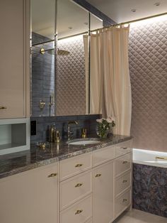 a bathroom with two sinks and a bathtub next to a window covered in curtains