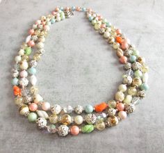 Absolutely beautiful vintage necklace - much better in person! Marked Hong Kong on hook. 19-21 inches (can adjust with extender) Very good condition, minor wear (some of the texture is worn on some beads). Features 3 strands of beads. Has an awesome variety of beads: sea foam green, aurora borealis pink/blue/clear, frosted white, surgared orange/green/white, textured white/brown, crackle white/gold, and gold swirl Green Aurora Borealis, Green Aurora, Pastel Beads, Twisted Metal, Viking Necklace, Vintage Japan, Locket Necklace, Glass Necklace, Sea Foam