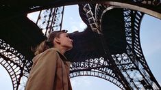 a woman standing in front of the eiffel tower looking up into the sky