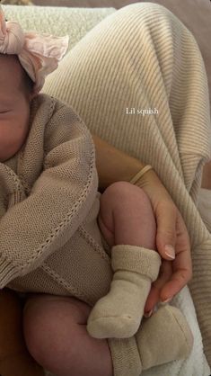 a newborn baby wearing a brown sweater and pink headband