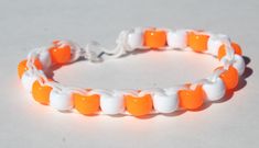 an orange and white beaded bracelet on a white surface with the beads in the shape of teeth