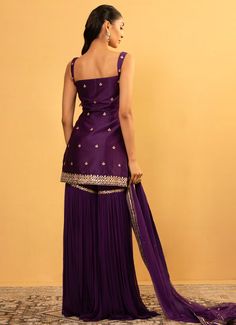 Embrace the timeless beauty and exquisite craftsmanship of the Purple Chanderi Embroidered Sharara Set, made from luxurious chanderi and georgette fabrics. The purple chanderi kurta, adorned with intricate champagne gota work, exudes elegance and sophistication, while the rich hue enhances its regal appeal. Paired with a flowy georgette sharara, this ensemble offers a perfect blend of traditional charm and modern flair. The accompanying net dupatta, edged with a delicate Chanderi border, adds a touch of grace and completes the look beautifully. Perfect for Home Pooja, festivals and family gatherings, this outfit ensures you make a stunning statement at any event. Composition : Kurta - Chanderi, Sharara - Georgette and Dupatta - Soft Net Care: Dry Clean Only and Vacuum Storage This product Georgette Sharara, Embroidered Sharara, Gota Work, Vacuum Storage, Sharara Suit, Indian Wedding Wear, Sharara Set, Net Dupatta, Georgette Fabric