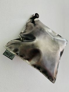 a metal object hanging on the wall with a tag attached to it's side