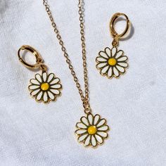 three pieces of jewelry on a white cloth with gold chains and flowers in the center