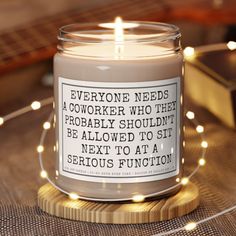 a candle with a quote on it sitting on a table next to some books and lights