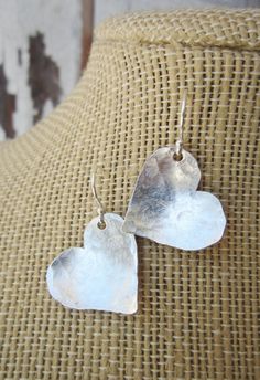 "I cut these two free form hearts from a sheet of sterling silver metal and hammered them to create these rustic earrings. They are coated to prevent tarnishing. The hearts have a slight curve to them to pick up shine from the hammered indensions. They measure 1 1/4\" in length from the top of the sterling silver earwire. Very lightweight and comfortable for all day wear. See the longer heart version here: https://www.etsy.com/listing/129416439/valentines-gift-sterling-silver-heart?ref=shop_home Metal Sheet Jewelry, Hammered Silver Heart Jewelry, Heart-shaped Hammered Sterling Silver Jewelry, Sterling Silver Earrings For Mother's Day Anniversary, Sterling Silver Earrings For Anniversary, Sterling Silver Earrings For Anniversary And Mother's Day, Silver Heart Earrings For Anniversary On Valentine's Day, Sterling Silver Earrings For Anniversary Gift, Silver Sterling Silver Earrings For Anniversary Gift