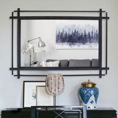 a living room with a large mirror on the wall next to a vase and lamp