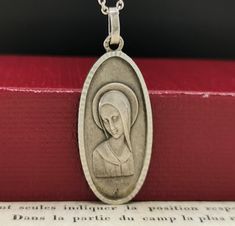 A beautiful genuine 1950s vintage solid silver Virgin Mary pendant in Art Deco style, floats from a  17-inch long 925 silver necklace. In good condition, would make a nice gift for someone special! Material: silver, hallmarked Pendant measures: 15 x 33 mm total weight (with chain): 6.5g Box on photos is NOT included! A stunning religious jewelry shop well worth a visit ... https://www.etsy.com/shop/SacredMagic Vintage Silver Necklaces For Memorial, Vintage White Gold Nickel-free Necklace, Vintage Necklace With Polished Finish For Gift, Vintage Engraved Necklace For Commemoration, Vintage Engraved Necklaces For Commemoration, Silver Oval Pendant Necklace For Commemoration, Silver Vintage Charm Jewelry For Commemoration, Silver Jewelry With Vintage Charm For Commemoration, Vintage Pendant Necklace For Commemoration