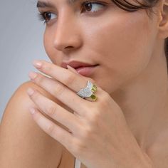 This ring from German Kabirski's Buds and Beans Collection challenges conventional design with its unique setting of two octagon-cut Peridot gemstones. One stone is set vertically, the other horizontally, embodying a design perfect for those who appreciate seeing things from multiple perspectives and find harmony in contrasts. The dual plating of White Rhodium and 18K Gold enhances the design's complexity, while the band's organic-like texture—a signature of Kabirski's work—adds an earthy, tacti Luxury Peridot Rings With Accent Stones, Luxury Multi-stone Peridot Ring, Luxury Peridot Multi-stone Rings, Anniversary Peridot Jewelry With Diamond Accents, Luxury Multi-stone Peridot Jewelry, Luxury Peridot Multi-stone Jewelry, Luxury Peridot Jewelry With Accent Stones, Fine Green Citrine Jewelry, Fine Jewelry With Peridot And Accent Stones