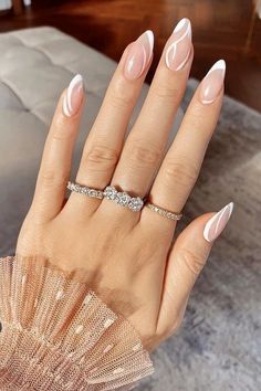 a woman's hand with pink and white manicured nails holding a diamond ring