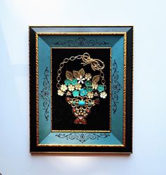 a painting on the wall that is decorated with beads and flowers in a blue frame