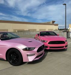 two pink mustangs are parked next to each other