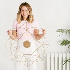 a woman holding up a golden geometric object