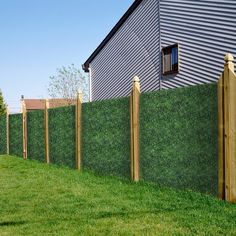 a fence that is next to a house with grass growing on the top and bottom